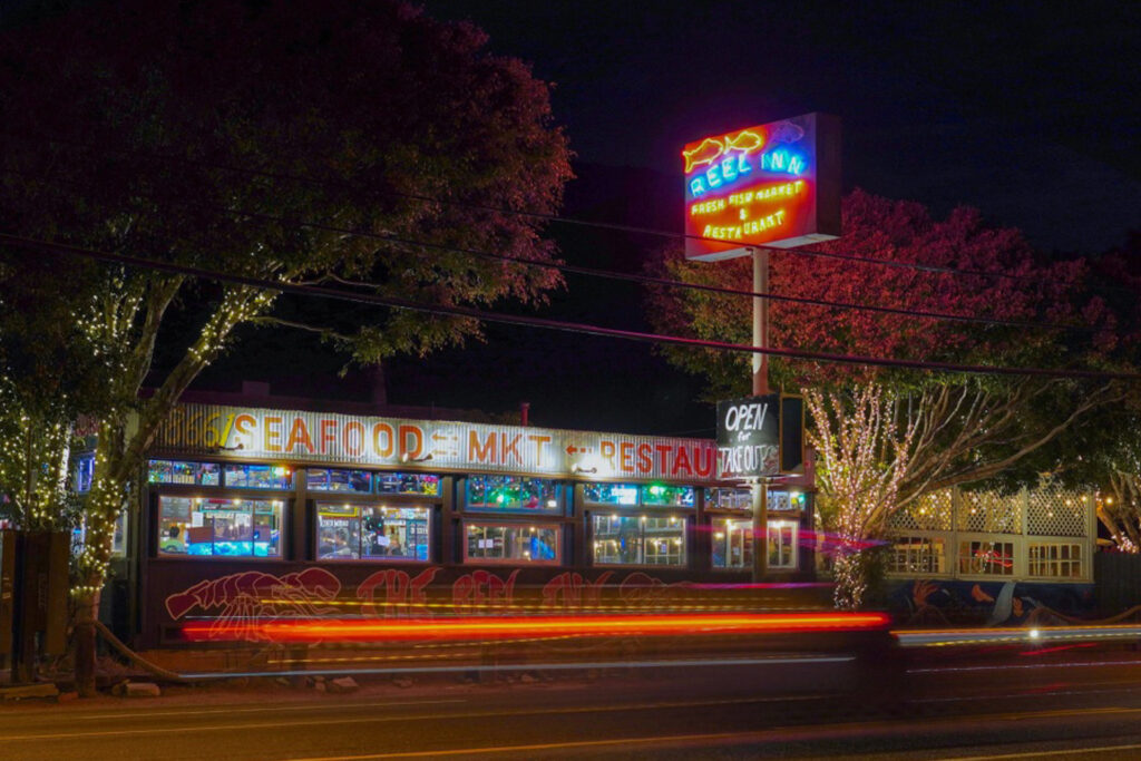Night time photo of Reel Inn and iconic neon sign taken from the beachside across Pacific Coast Highway.